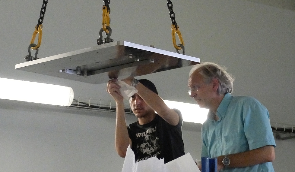Installation of an implanter's top flange photo of two people cleaning a large suspended rectangular flange