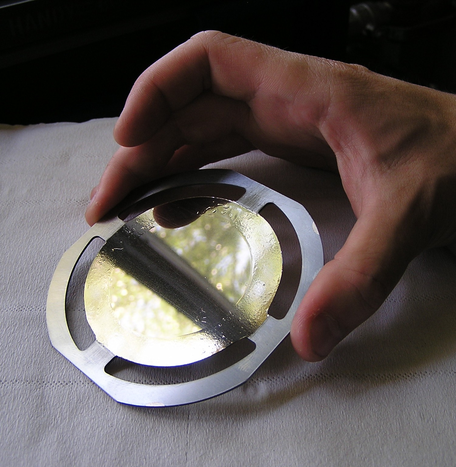Mylar® foil on a metallic holder, with the deposit realized by multi beam sputtering Photo of bare hands holding a Ø100mm Mylar® foil on a metallic holder, with a deposit realized by multi beam sputtering
