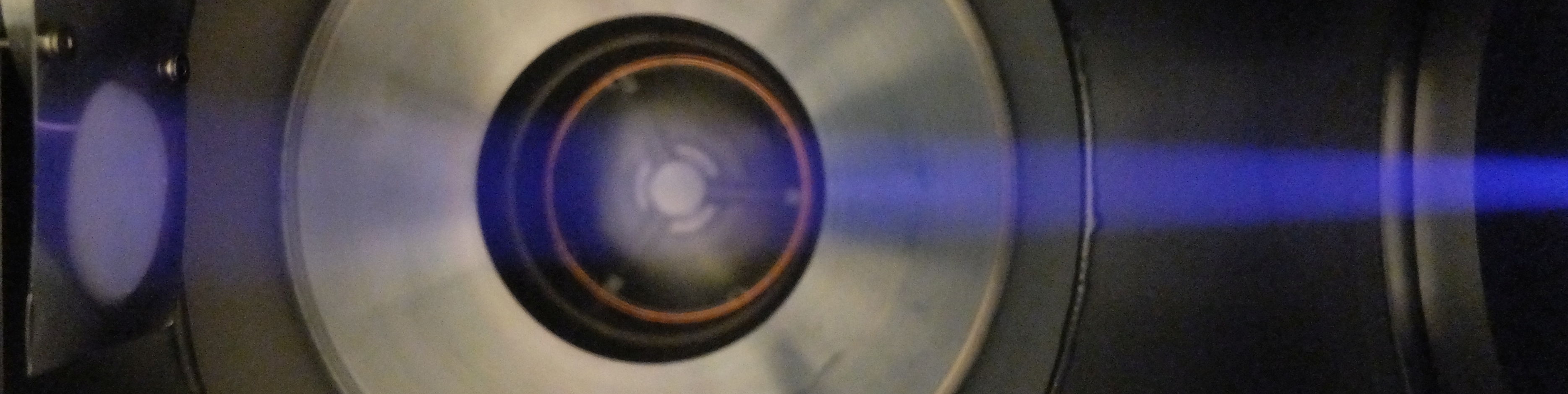 Interior of the multifunctional surface treatment system, with an Ar ion beam nanostructuring a sample over Ø30mm Photo of interior of multifunctional surface treatment system, with a slightly divergent Ar ion beam nanostructuring a sample over Ø30mm
