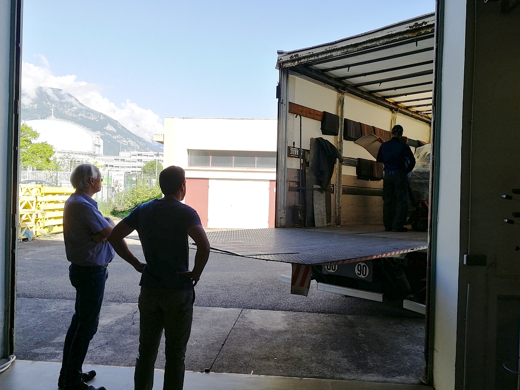 Shipment of our first 24-sources based ion beam deposition system Photo of two people watching the loading of a 24-sources based ion beam deposition system into a truck
